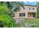 Home's rear exterior featuring a large yard, a covered patio, and manicured tropical landscaping at 10925 Oyster Bay Cir, New Port Richey, FL 34654