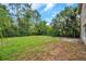 Grassy backyard with trees and bushes surrounding the exterior of the home at 10925 Oyster Bay Cir, New Port Richey, FL 34654