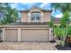 A two-story exterior elevation of a tan home with a three-car garage and a paver driveway at 10925 Oyster Bay Cir, New Port Richey, FL 34654
