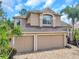 Exterior elevation with a three-car garage, a paver driveway, and lush, mature landscaping at 10925 Oyster Bay Cir, New Port Richey, FL 34654