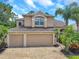Charming home features a three-car garage, tan stucco, and a beautifully brick paved driveway, with tropical landscaping at 10925 Oyster Bay Cir, New Port Richey, FL 34654