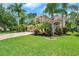 Beautifully landscaped front yard with mature trees, colorful shrubs, and a brick paver driveway at 10925 Oyster Bay Cir, New Port Richey, FL 34654