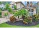 Beautifully landscaped front yard with mature trees, colorful shrubs, and a brick paver driveway at 10925 Oyster Bay Cir, New Port Richey, FL 34654