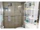 Tiled shower with grab bar, shelving above toilet, and vanity in accessible bathroom at 11810 Oceanside Dr, Port Richey, FL 34668