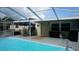 Backyard patio featuring a screened in pool, dining table, and a grill, perfect for outdoor entertaining at 11810 Oceanside Dr, Port Richey, FL 34668
