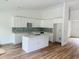 Bright kitchen with white cabinets, a center island, modern backsplash and wood-look flooring at 14586 Mocking Wren Rd, Weeki Wachee, FL 34614