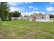 Wide shot of the backyard with a mobile home featuring gray siding and a grassy field at 16104 Naples St, Brooksville, FL 34604