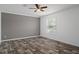Bedroom with a neutral gray accent wall, wood-look floors, a ceiling fan, and bright window at 16104 Naples St, Brooksville, FL 34604