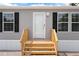 Close up of front door and wood stairs with black shutters at 16104 Naples St, Brooksville, FL 34604