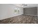 Bright living room featuring wood-look flooring, large windows, and neutral walls, enhanced by a ceiling fan at 16104 Naples St, Brooksville, FL 34604