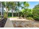 A stone-paved backyard patio and fire pit with palm trees, hedges, and professional landscaping at 1831 Cardamon Dr, Trinity, FL 34655