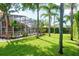Beautiful backyard with green grass, palm trees, and a screened-in pool area at 1831 Cardamon Dr, Trinity, FL 34655