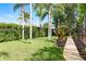 Lush backyard with green grass, palm trees, and well-kept landscaping at 1831 Cardamon Dr, Trinity, FL 34655