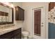 Bathroom with dark wood cabinets, granite countertop, toilet, and decorative door at 1831 Cardamon Dr, Trinity, FL 34655