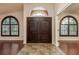 Grand entryway featuring dark, solid wood double doors, arched windows and beautiful tile and hardwood flooring at 1831 Cardamon Dr, Trinity, FL 34655