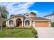 Stunning single Gathering home with a well-manicured lawn, large arched windows, and a two-car garage in a suburban neighborhood at 1831 Cardamon Dr, Trinity, FL 34655
