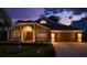 Inviting front exterior of a home, showcasing arched windows, a two-car garage, and well-kept landscaping at 1831 Cardamon Dr, Trinity, FL 34655