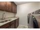 A laundry room featuring granite counters, dark cabinets, stainless steel sink, and new washer and dryer at 1831 Cardamon Dr, Trinity, FL 34655
