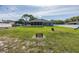 Well-manicured backyard with lush green grass, featuring a fire pit and an enclosed patio area at 2027 Fentress Ct, Spring Hill, FL 34609