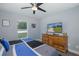 This is a well-lit bedroom featuring carpet flooring and a wooden dresser with a large TV at 2027 Fentress Ct, Spring Hill, FL 34609