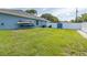 Exterior shot showcasing the lush lawn and kayaks attached to the house's exterior, all surrounded by a white privacy fence at 2027 Fentress Ct, Spring Hill, FL 34609