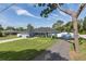 Attractive one-story home featuring a gravel driveway, lush green lawn, and vibrant light blue facade at 2027 Fentress Ct, Spring Hill, FL 34609