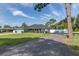 Inviting one-story home boasting a gravel driveway, green lawn, and attractive light blue facade at 2027 Fentress Ct, Spring Hill, FL 34609