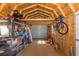 Shed interior with open rafters, plywood walls and concrete floor, equipped with shelving and lots of storage at 2027 Fentress Ct, Spring Hill, FL 34609