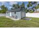 Exterior view of the blue shed featuring a roll up door and a side entry door with a ramp at 2027 Fentress Ct, Spring Hill, FL 34609