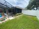 Grassy backyard with landscaping, fenced perimeter, and screened-in patio at 3128 Montague Ave, Spring Hill, FL 34608