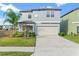 Charming two-story home featuring a two-car garage, well-maintained lawn, and complemented by a beautiful palm tree at 313 Argyll Dr, Spring Hill, FL 34609