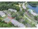 An aerial view of condos shows parking, tennis courts, pool, trees, and lakeside living at 3153 Lake Pine Way # A1, Tarpon Springs, FL 34688