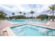 Outdoor community swimming pool and jacuzzi surrounded by lounge chairs at 3153 Lake Pine Way # A1, Tarpon Springs, FL 34688