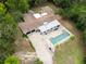 Aerial view of a home, lush greenery, a sparkling pool, and a spacious paved patio area at 34955 Blanton Rd, Dade City, FL 33523
