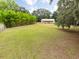 A sprawling green backyard with a structure in the distance, enclosed by fencing and mature trees at 34955 Blanton Rd, Dade City, FL 33523