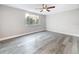 Bedroom featuring light grey wood-look flooring, a ceiling fan, and a window overlooking greenery at 3545 Landale Dr, Holiday, FL 34691