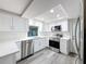 Kitchen featuring stainless steel appliances and white cabinets with modern hardware and gray wood floors at 3545 Landale Dr, Holiday, FL 34691