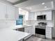 Modern kitchen featuring white cabinets, stainless steel appliances, quartz countertops and gray wood flooring at 3545 Landale Dr, Holiday, FL 34691