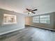 Open living room features new grey floors and ceiling fan and pass-through to kitchen at 3545 Landale Dr, Holiday, FL 34691
