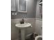 Cozy half bathroom with a pedestal sink, decorative mirror, and neutral gray paint at 5710 Broadway Ave, New Port Richey, FL 34652