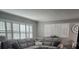 Comfortable living room featuring large windows, neutral-toned sectional, and white shutters for enhanced privacy at 5710 Broadway Ave, New Port Richey, FL 34652