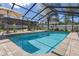 Refreshing screened-in pool with brick patio features steps and an umbrella for leisurely dips and relaxation at 6347 Shadydale Ave, Spring Hill, FL 34609