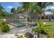 A screened-in pool is surrounded by tropical plants and lounge chairs for relaxing in the Florida sunshine at 6347 Shadydale Ave, Spring Hill, FL 34609