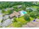 An aerial view of condo buildings, the community pool, and tennis courts surrounded by lush greenery at 6462 River Run Blvd, Weeki Wachee, FL 34607