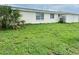 A view of the backyard of the property, featuring an overgrown grassy area and minimal landscaping at 7714 Fox Hollow Dr, Port Richey, FL 34668