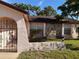Exterior view of home featuring a stone facade, arched entryway, and a well-maintained lawn at 8516 Inwood Dr, Hudson, FL 34667