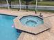Close up of a hot tub with a flamingo floating in the nearby pool and a serene lake backdrop at 9188 Mississippi Run, Weeki Wachee, FL 34613
