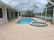 Screened pool and spa surrounded by light brick patterned deck with lake view at 9188 Mississippi Run, Weeki Wachee, FL 34613