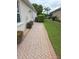 A side yard featuring a brick walkway, manicured lawn, and privacy bushes at 9188 Mississippi Run, Weeki Wachee, FL 34613