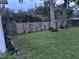 Large backyard with a wooden fence, lush grass, and mature trees at 9536 Mayson St, New Port Richey, FL 34654